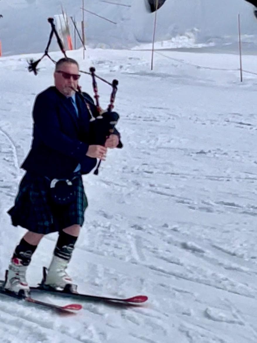Bagpiper playing Highland pipes on a ski slope